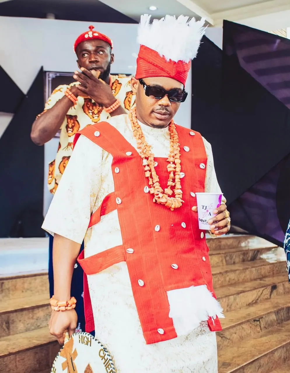 Chief in a cream and red ceremonial outfit with coral beads
