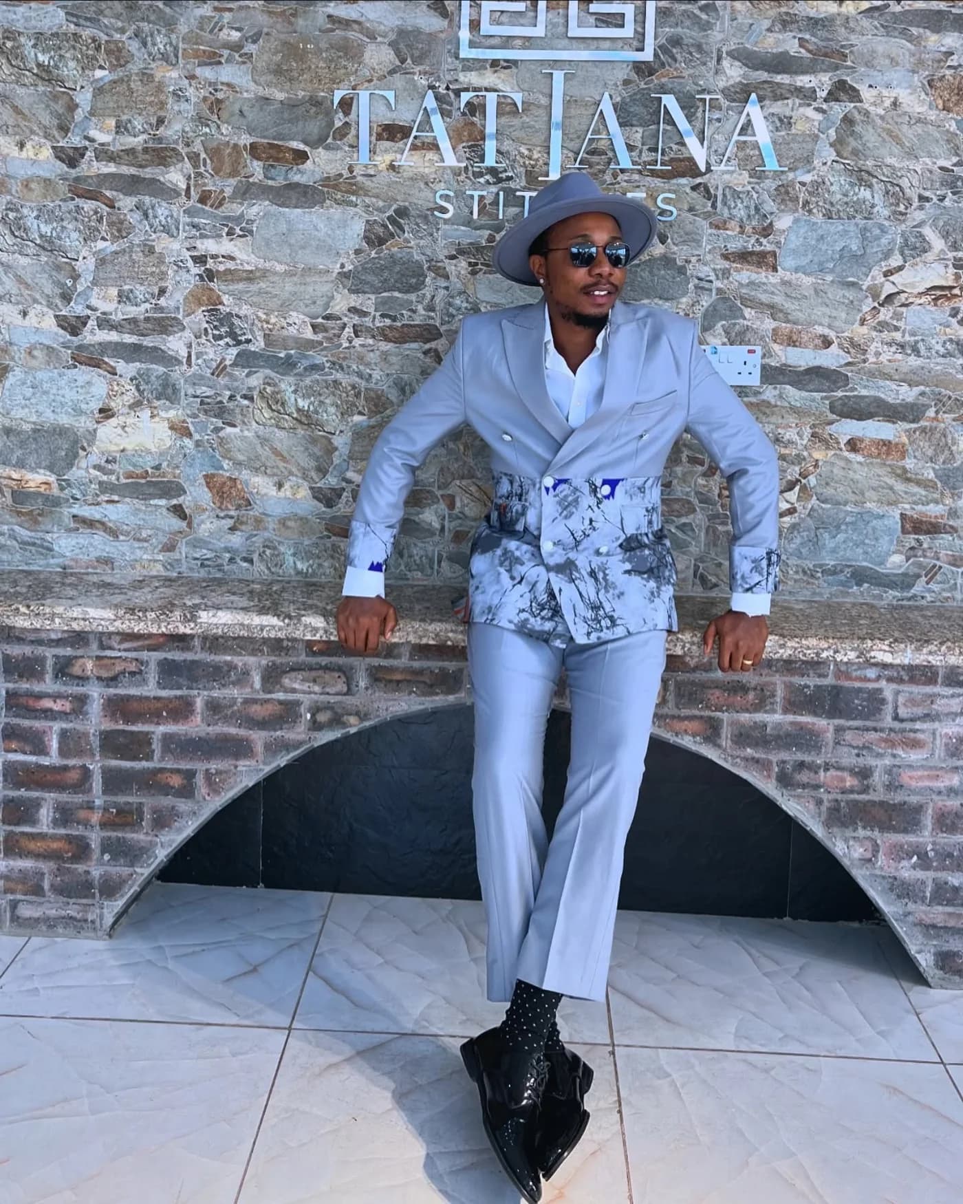 Grey embroidered suit against the stone wall